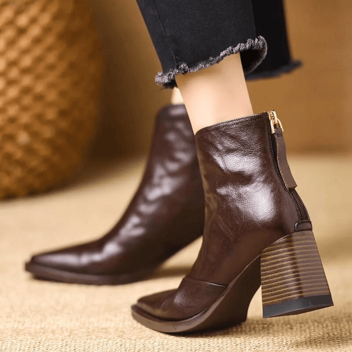 A woman in tailored pants wearing polished mid-heel ankle boots with a back zip.