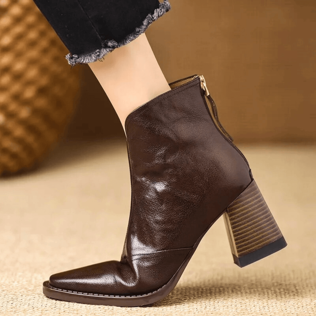 A woman in tailored pants wearing polished mid-heel ankle boots with a back zip.