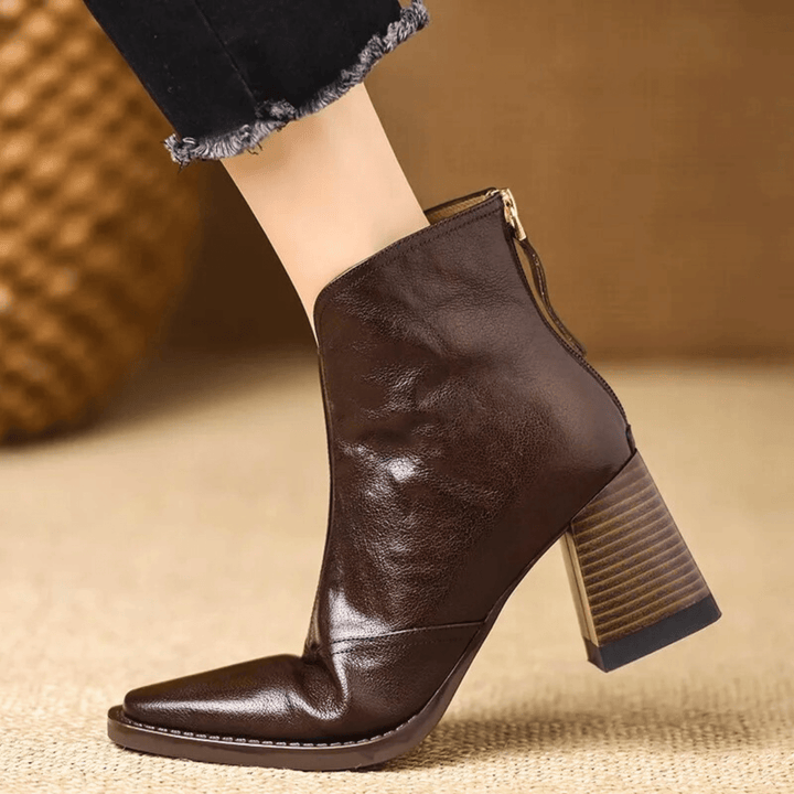 A woman in tailored pants wearing polished mid-heel ankle boots with a back zip.
