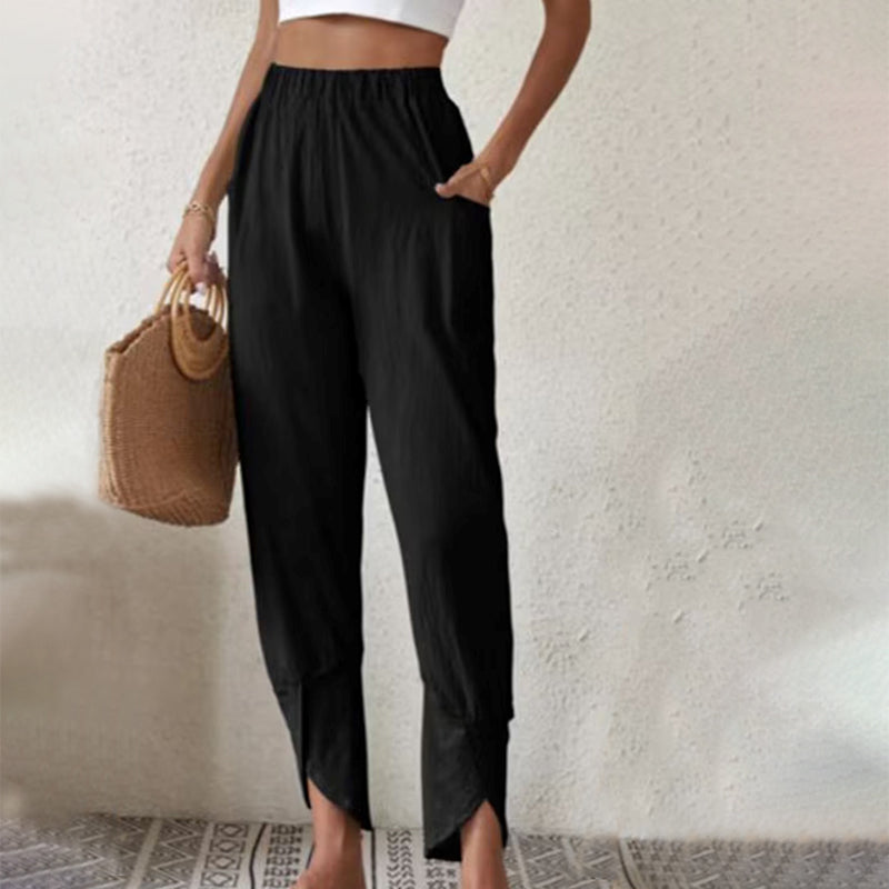 Woman wearing tapered pants with a slit hem at the ankle, walking near the coast.