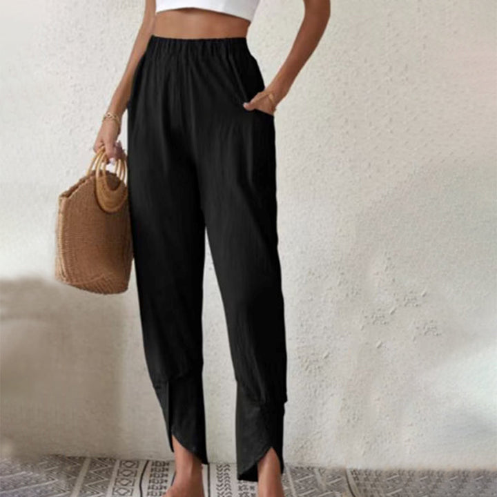 Woman wearing tapered pants with a slit hem at the ankle, walking near the coast.